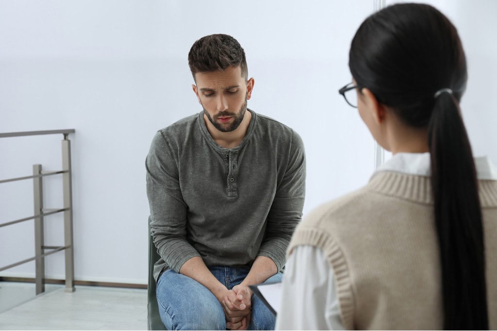 A man sits opposite a counselor, looking introspective during a private session. This setting represents personal guidance and support, essential in Fentanyl rehab in Reseda CA.
