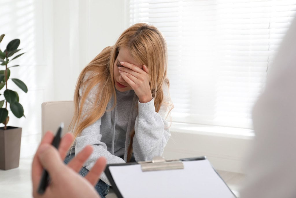 A woman sitting with her head in her hands during a counseling session, depicting the emotional struggles involved in addiction. This image symbolizes the support available through cocaine rehab in Reseda CA.