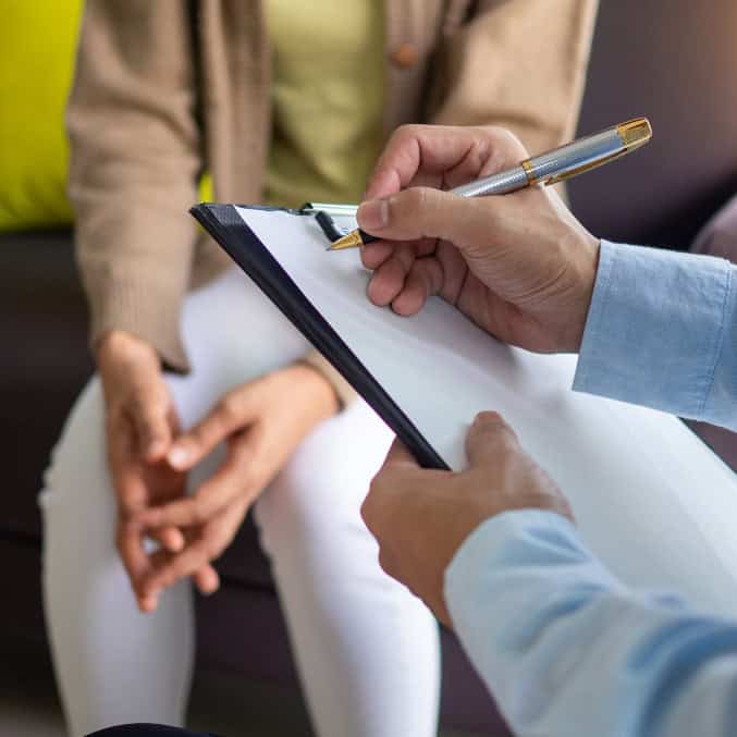 A counselor taking notes while listening attentively to a patient during a session, symbolizing compassionate and professional support for addiction treatment in Reseda CA.
