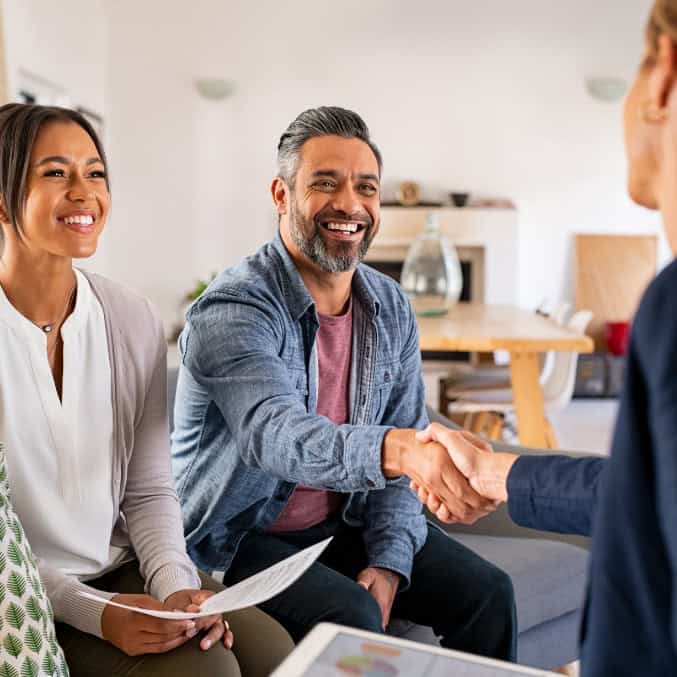 A happy couple shakes hands with a professional in an office setting, representing the supportive and welcoming environment at an addiction treatment center in Reseda, CA.