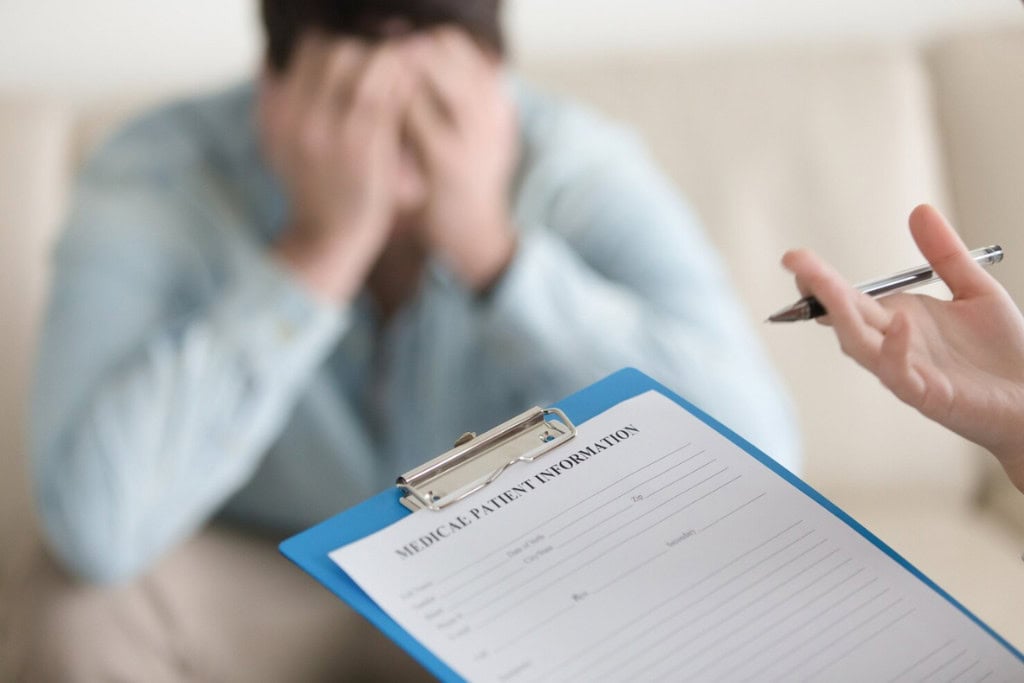 A patient holds his head in frustration during an intake session for dual diagnosis treatment in Reseda CA.