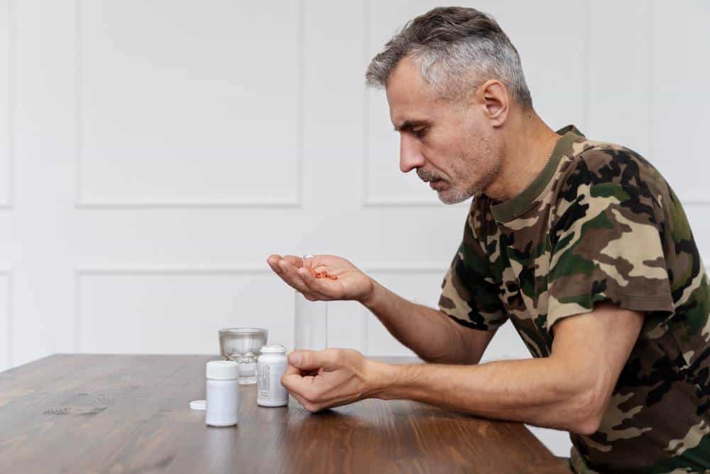 Man in camouflage shirt examining pills as part of his cocaine detox in Reseda CA.