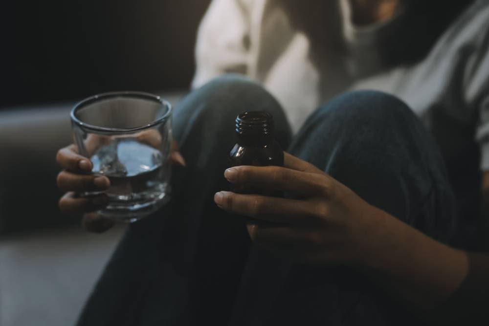 Person holding a glass of water and a small medicine bottle, representing the first steps of Opiate Detox in Reseda, CA.