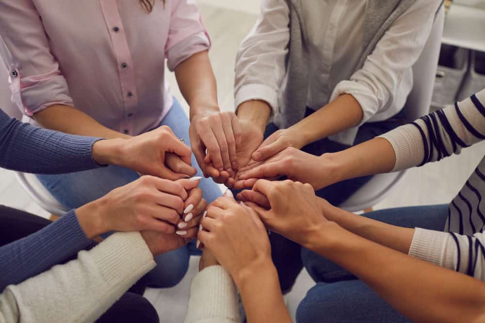 Support group joining hands during meth detox recovery in Reseda, CA.